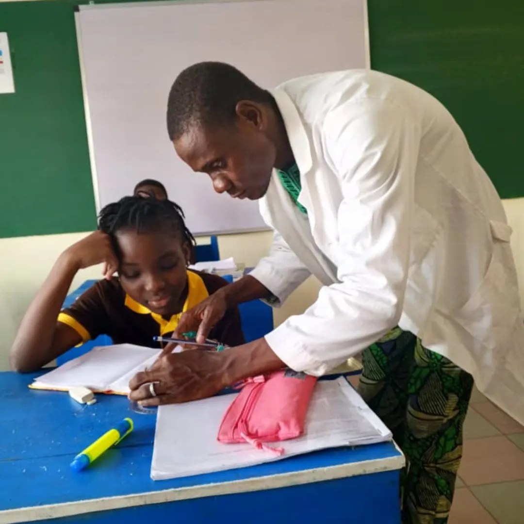 A teacher helping a pupil with her notebook in class