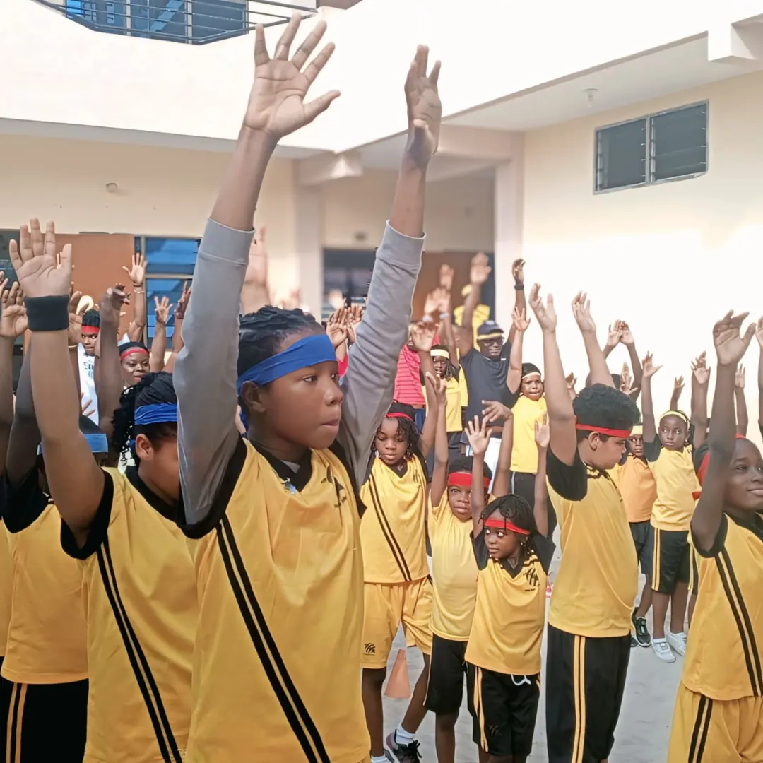 Pupils in school uniform raising their arms during an assembly