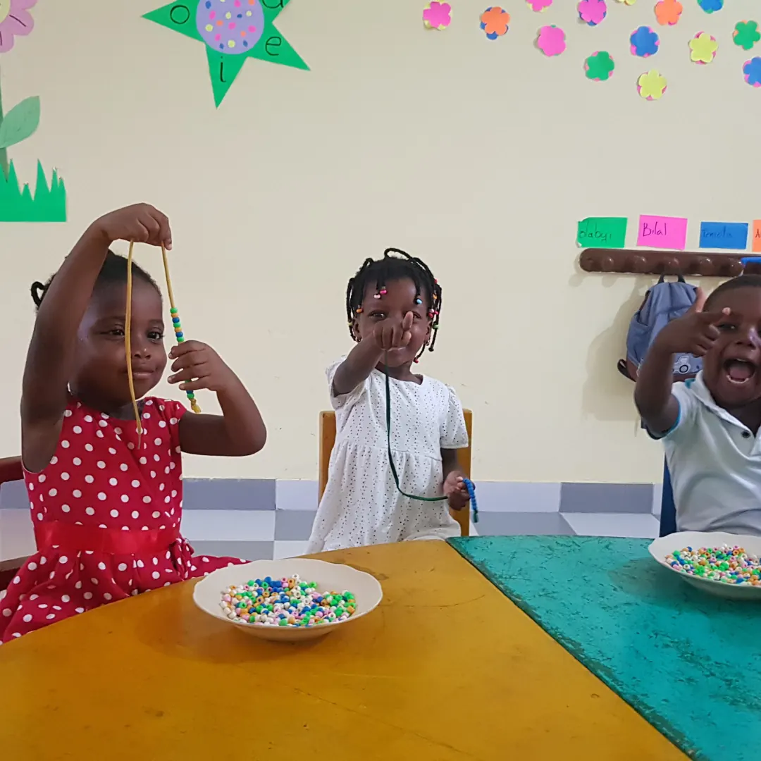 Young pupils threading colourful beads at a table