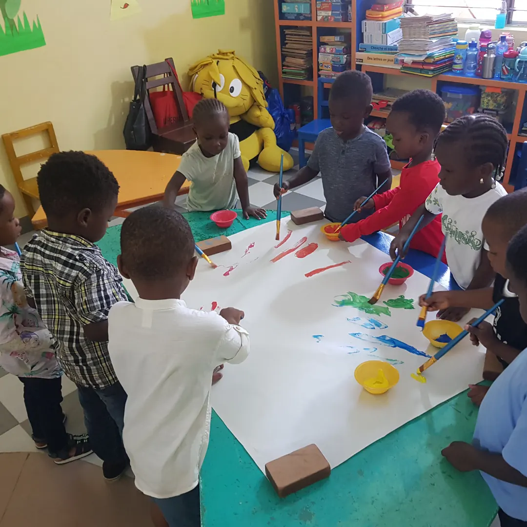Kindergarten children painting together on a large sheet of paper